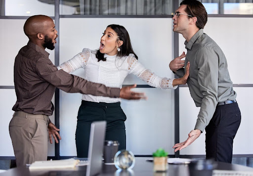 A woman attempts to break up a heated argument between two men at work