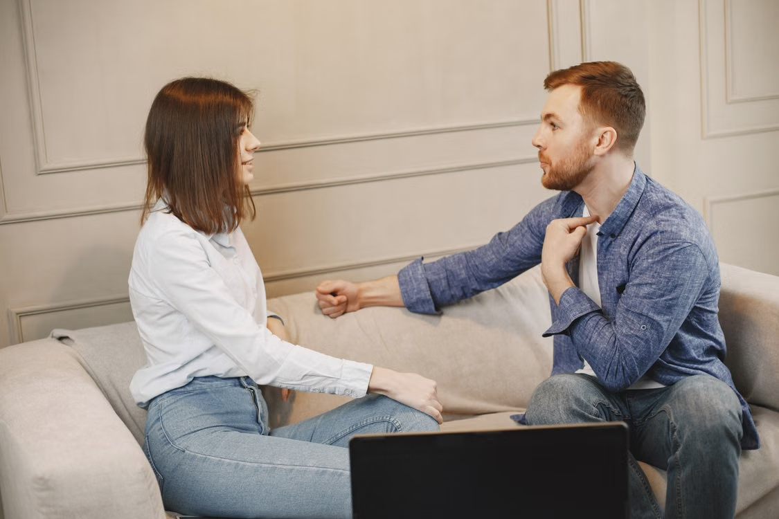 a man and a woman sitting on the couch talking